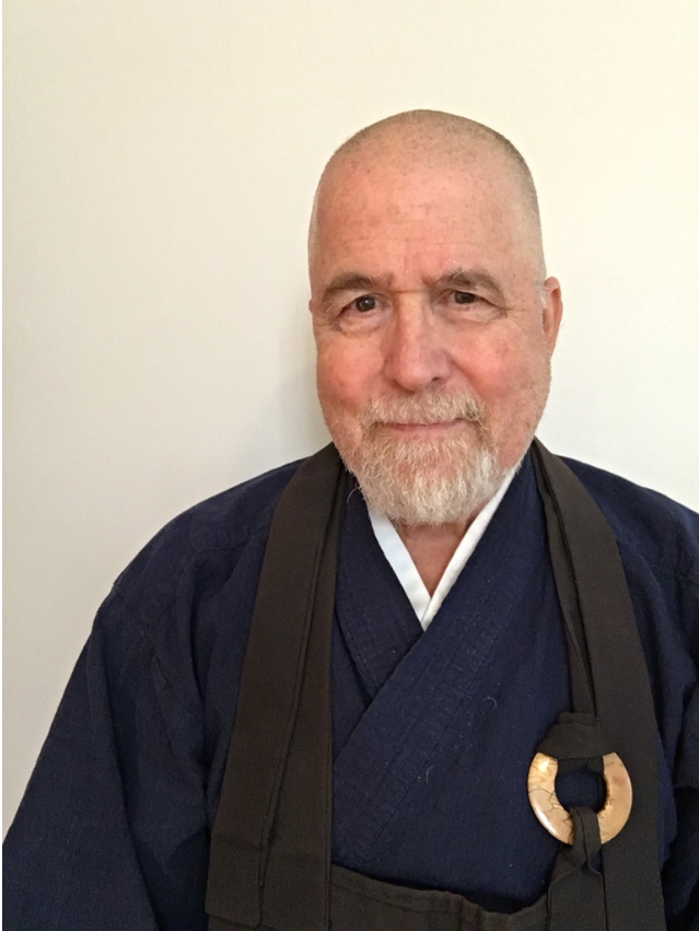 Headshot of the Rev. Edward Keido Sanshin Oberholtzer: a smiling man with shaved head wearing traditional vestments of a Zen Buddhist priest.